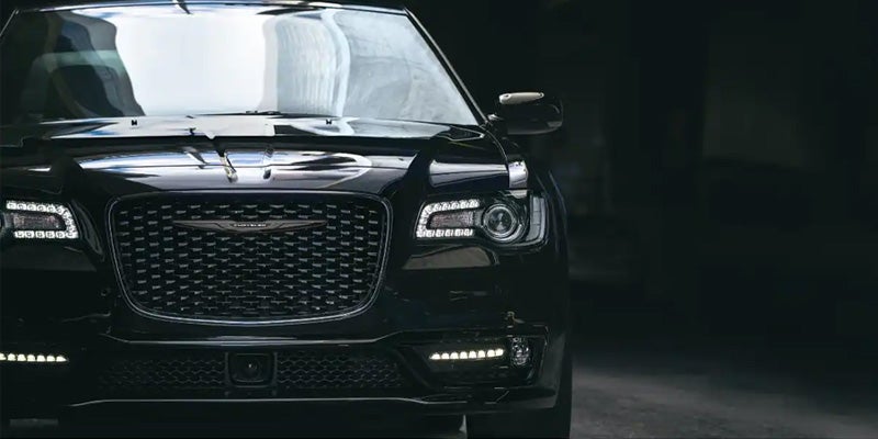 Front view of a dark grey Chrysler 300 with headlights and lower LED lights illuminated