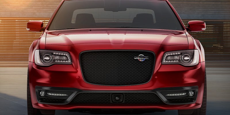 Front view of a shiny red Chrysler 300 sedan with a black honeycomb grille and LED headlights