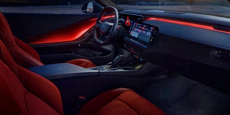 Interior of a sporty car with red racing seats, red ambient lighting along the dashboard and doors, and a digital display
