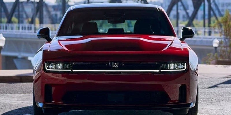 Front view of a dark red Dodge Charger Daytona SRT, featuring a wide light bar across the grille