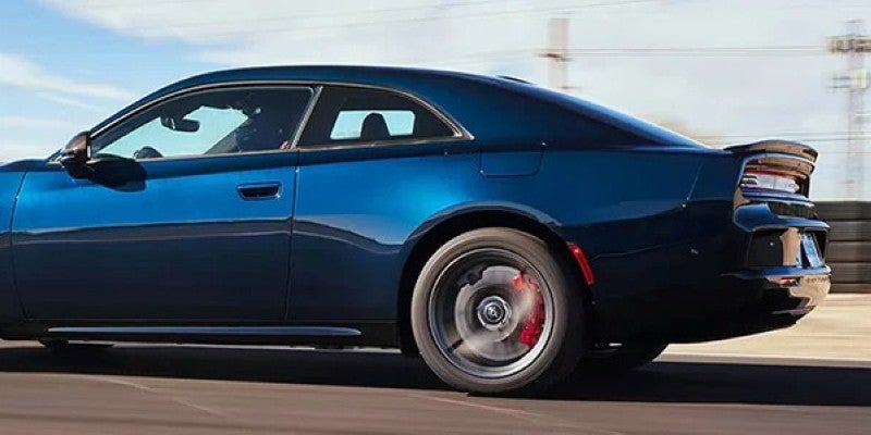 Side view of a dark blue two-door coupe with red brake calipers, moving quickly on a track.
