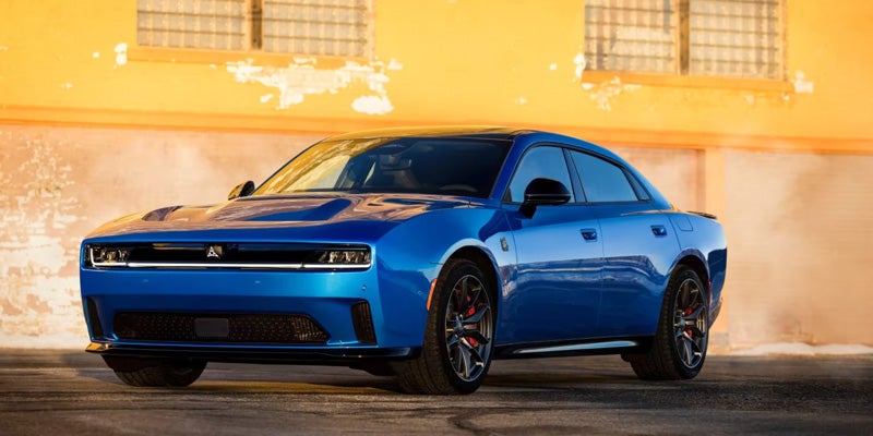 Front-left view of a blue Dodge Charger Daytona parked in front of a yellow wall