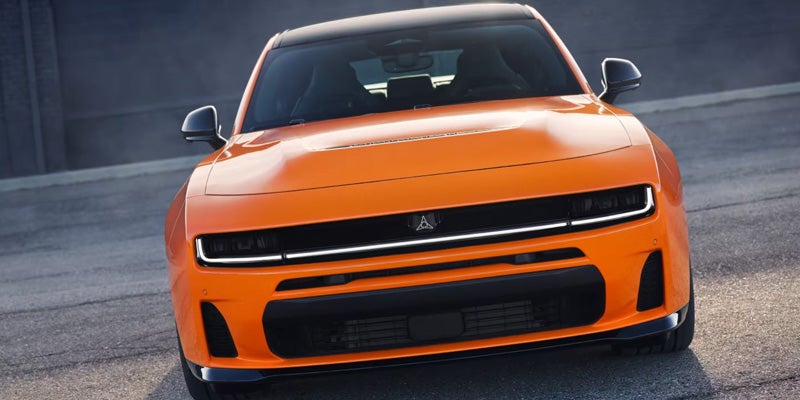 Frontal view of a bright orange electric Dodge Charger concept car with a black grille and roof